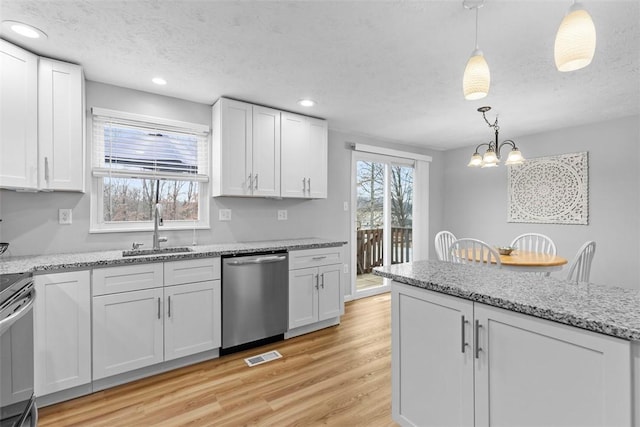 kitchen featuring sink, stainless steel appliances, white cabinets, decorative light fixtures, and light wood-type flooring