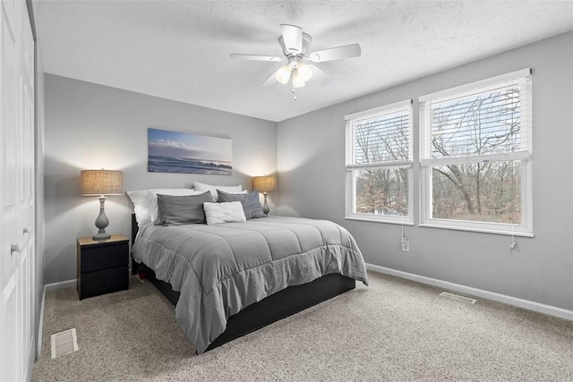 carpeted bedroom with ceiling fan and a textured ceiling