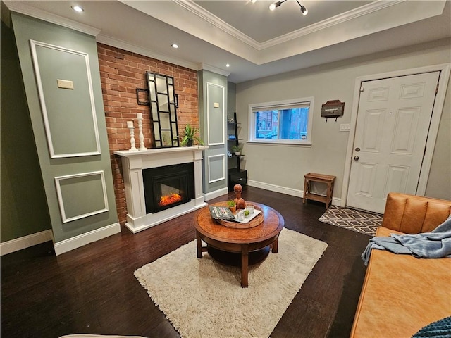 living room with a tray ceiling, dark wood-type flooring, and crown molding