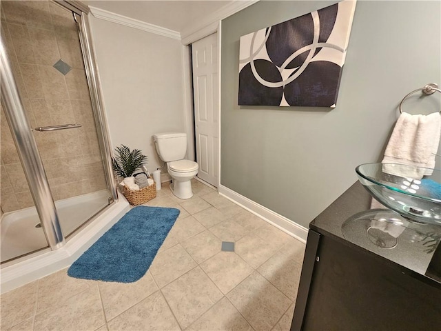 bathroom with a shower with shower door, tile patterned floors, toilet, vanity, and crown molding