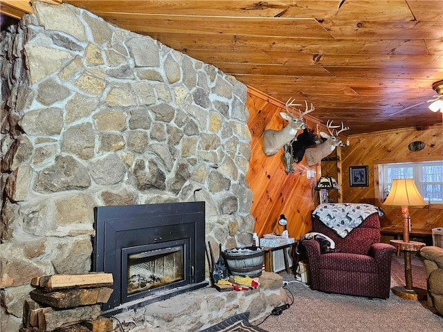 living area with wooden walls, wood ceiling, a fireplace, and carpet