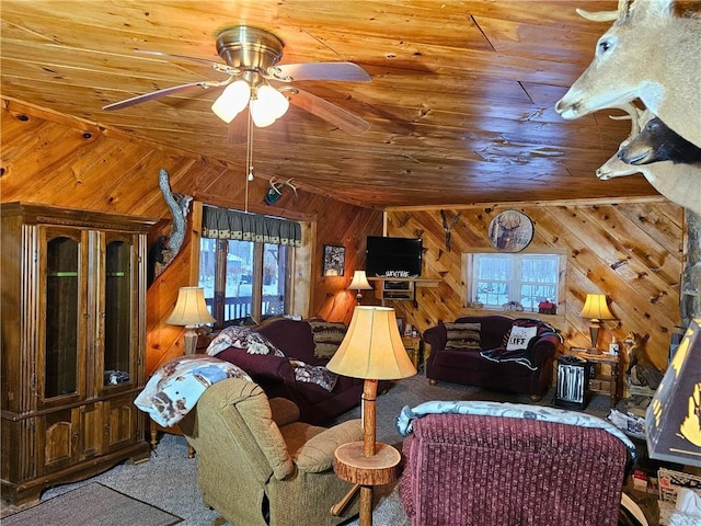 living area featuring a wealth of natural light, wood walls, wooden ceiling, and a ceiling fan