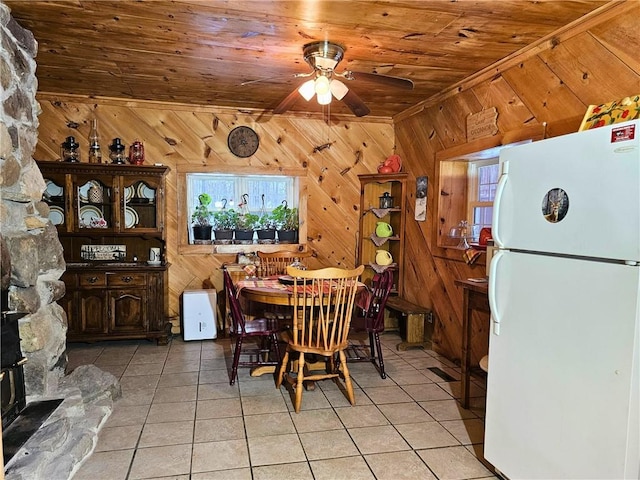 dining space featuring light tile patterned floors, wood walls, wood ceiling, and a ceiling fan