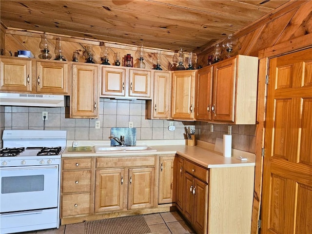 kitchen featuring gas range gas stove, under cabinet range hood, light countertops, wooden ceiling, and a sink