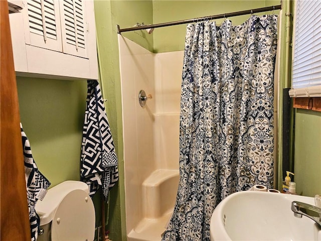 bathroom with curtained shower, toilet, and a sink