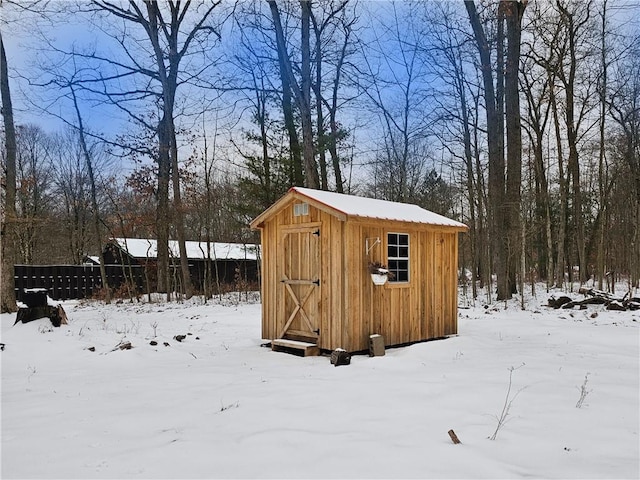 snow covered structure featuring an outdoor structure and a storage unit