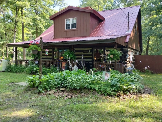 view of front of house with log siding, metal roof, and a front yard