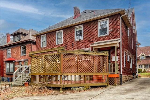 rear view of property featuring brick siding and a chimney