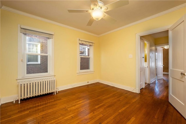 spare room with dark wood-style floors, ornamental molding, and radiator heating unit