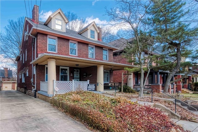 traditional style home featuring an outbuilding, a porch, and brick siding