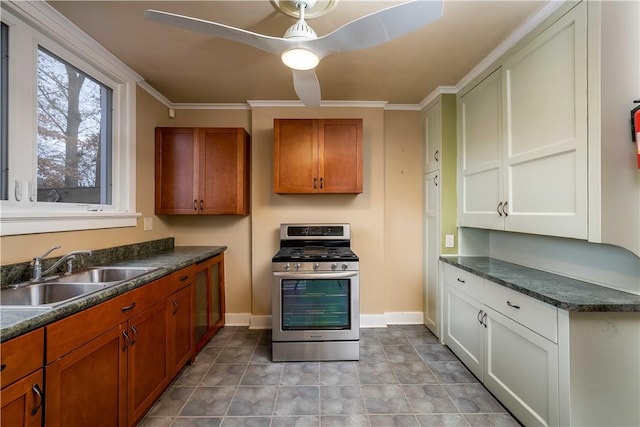 kitchen featuring baseboards, dark countertops, gas range, brown cabinets, and a sink