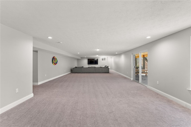 unfurnished living room with light colored carpet and a textured ceiling