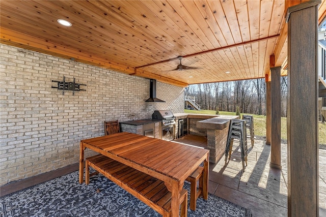 view of patio featuring a grill, exterior bar, area for grilling, and ceiling fan