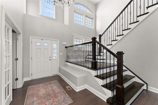 foyer featuring dark hardwood / wood-style floors, a chandelier, and a towering ceiling