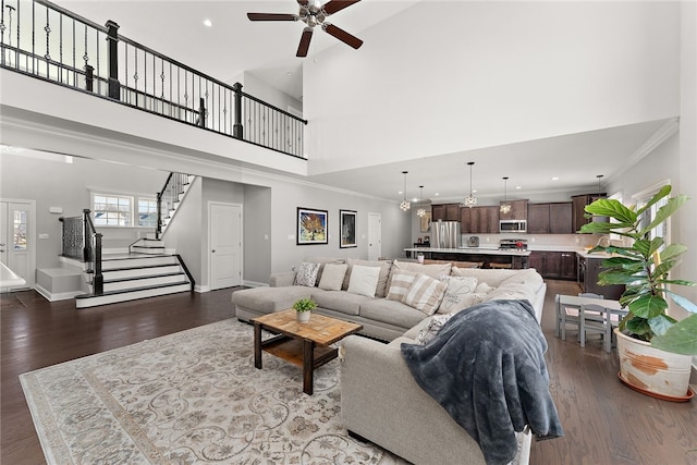 living room with crown molding, wood-type flooring, ceiling fan, and a high ceiling