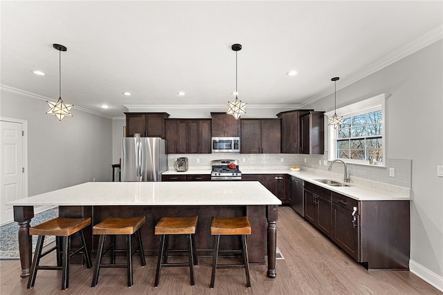 kitchen with pendant lighting, stainless steel appliances, a center island, and sink