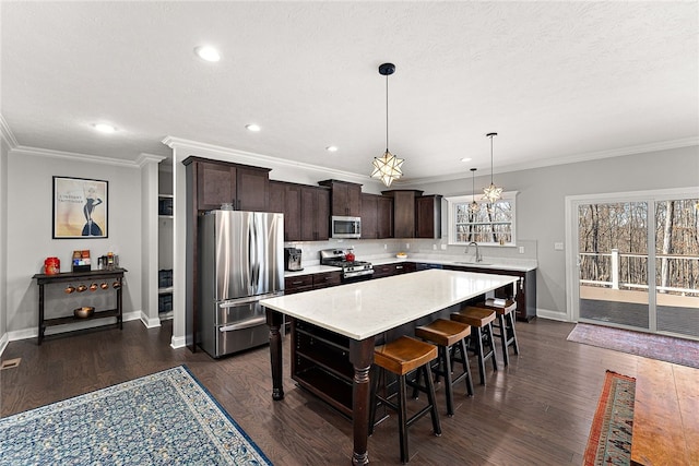 kitchen featuring sink, appliances with stainless steel finishes, dark hardwood / wood-style flooring, a kitchen island, and pendant lighting