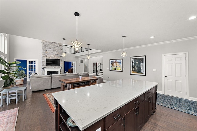 kitchen featuring dark hardwood / wood-style flooring, a center island, light stone counters, and a fireplace