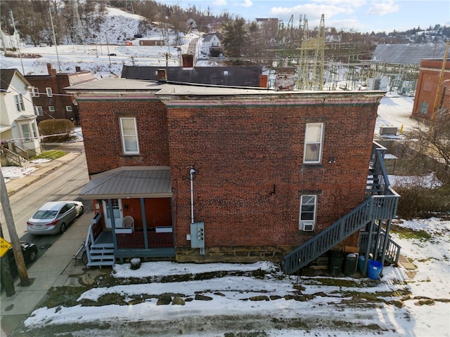 snow covered back of property with covered porch