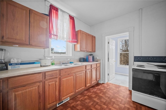 kitchen featuring dark parquet flooring, sink, and electric range