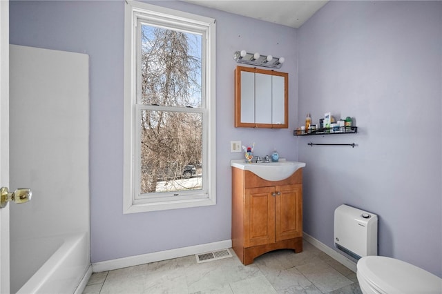 bathroom featuring vanity, a tub to relax in, and toilet