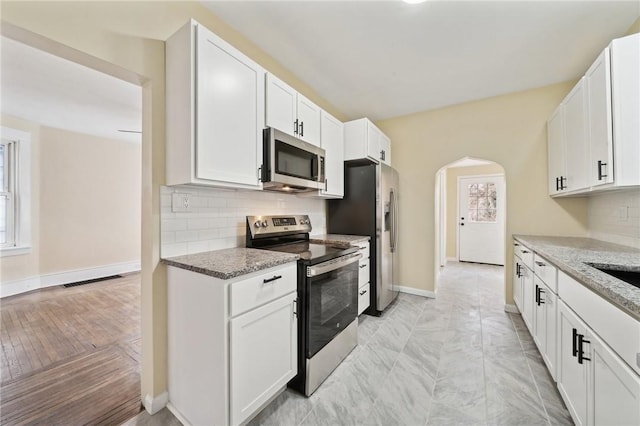 kitchen with stainless steel appliances, white cabinets, and light stone counters