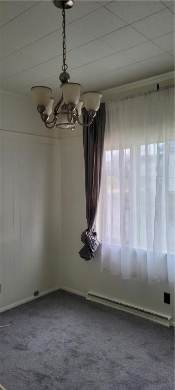 empty room featuring crown molding, a chandelier, plenty of natural light, carpet flooring, and a baseboard heating unit