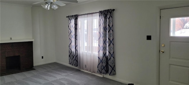 carpeted living room with a brick fireplace, crown molding, and ceiling fan