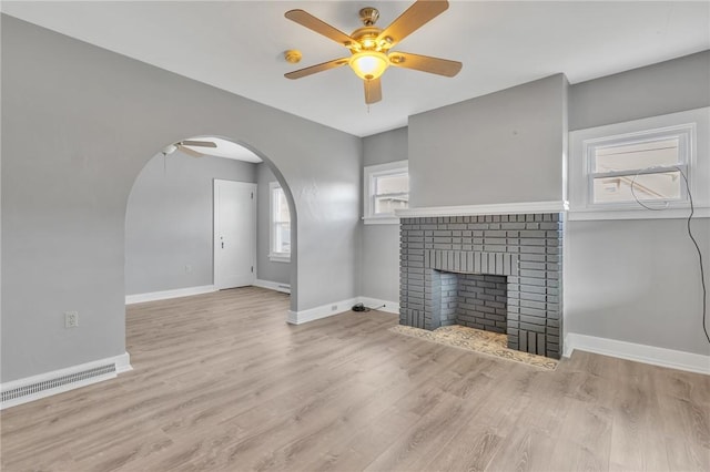 unfurnished living room with ceiling fan, a fireplace, and light hardwood / wood-style floors