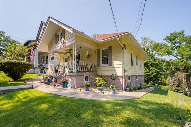 rear view of property featuring a lawn and covered porch