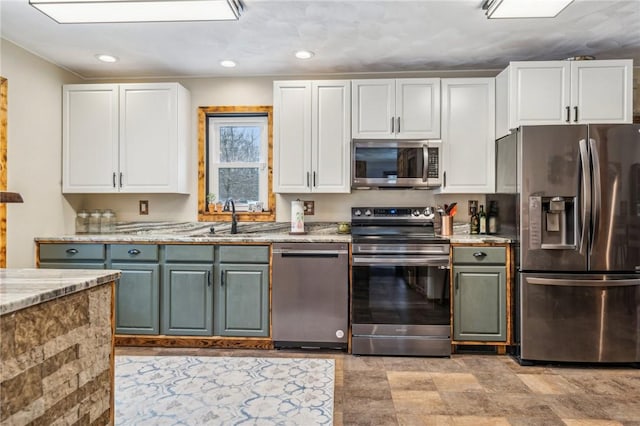 kitchen featuring appliances with stainless steel finishes, sink, white cabinets, and light stone counters