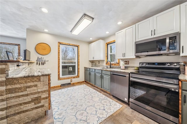 kitchen with stainless steel appliances, gray cabinets, sink, and white cabinets