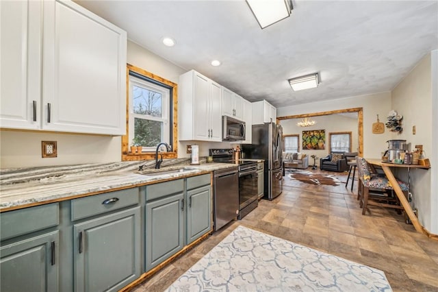 kitchen featuring a wealth of natural light, sink, white cabinets, stainless steel appliances, and an inviting chandelier