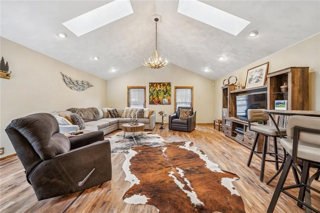 living room with a chandelier, vaulted ceiling with skylight, and light hardwood / wood-style floors