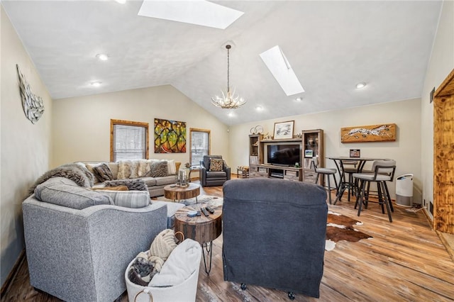 living room featuring hardwood / wood-style floors, vaulted ceiling with skylight, and a notable chandelier