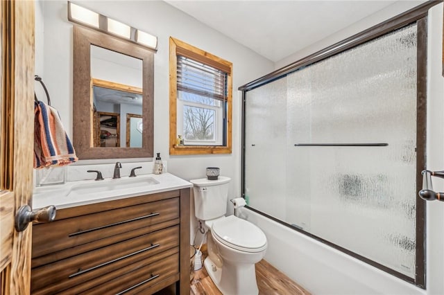 full bathroom featuring vanity, wood-type flooring, toilet, and combined bath / shower with glass door