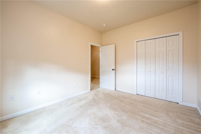 unfurnished bedroom featuring light carpet and a closet