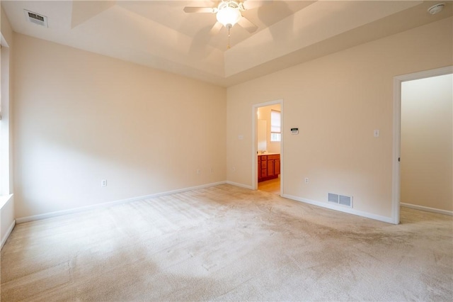 spare room featuring ceiling fan, a raised ceiling, and light carpet