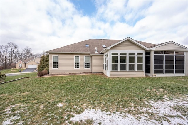 back of property featuring a garage, a sunroom, and a yard