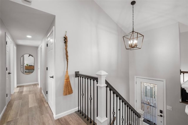 hall with a notable chandelier, vaulted ceiling, and light wood-type flooring