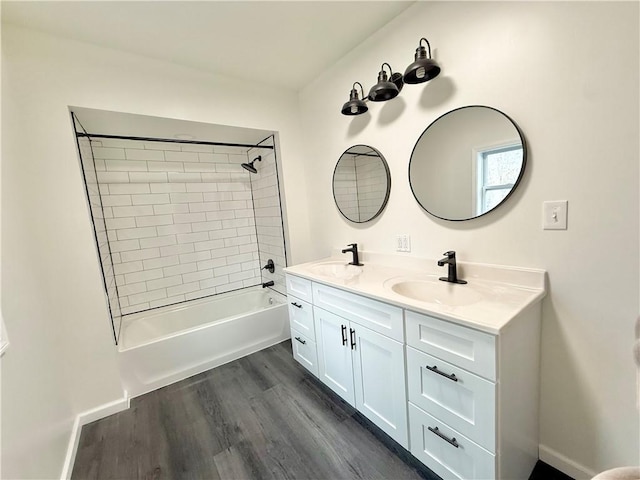 bathroom with wood-type flooring, tiled shower / bath combo, and vanity