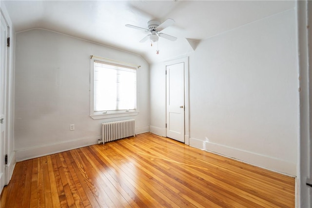 unfurnished bedroom with ceiling fan, lofted ceiling, radiator, and light hardwood / wood-style floors