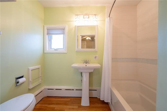 bathroom with wood-type flooring, a baseboard heating unit, shower / tub combo with curtain, and toilet