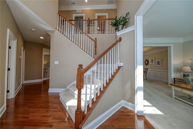 stairway with hardwood / wood-style flooring, crown molding, and a towering ceiling