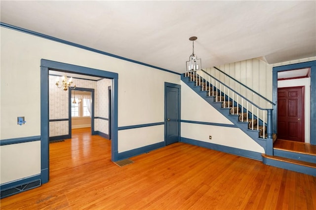 interior space featuring an inviting chandelier, hardwood / wood-style floors, and ornamental molding