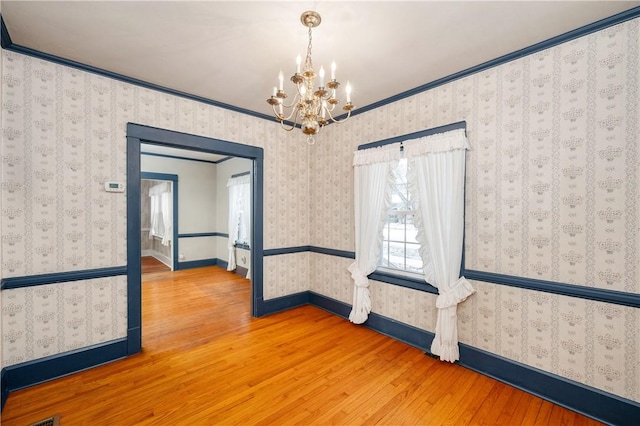 unfurnished room featuring ornamental molding, wood-type flooring, and a notable chandelier