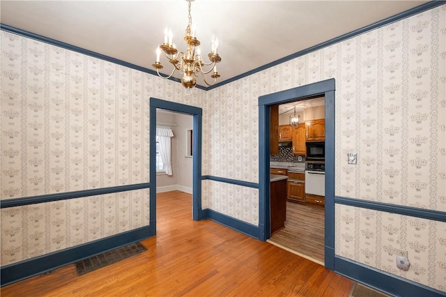 interior space featuring ornamental molding, hardwood / wood-style floors, and a notable chandelier