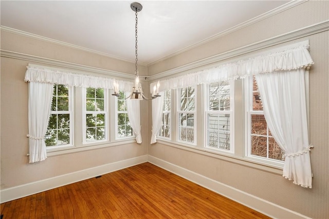 unfurnished dining area with an inviting chandelier, ornamental molding, and hardwood / wood-style floors