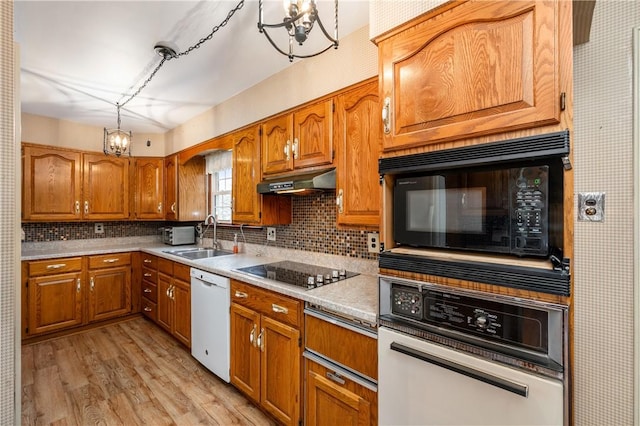 kitchen with sink, backsplash, light wood-type flooring, and black appliances