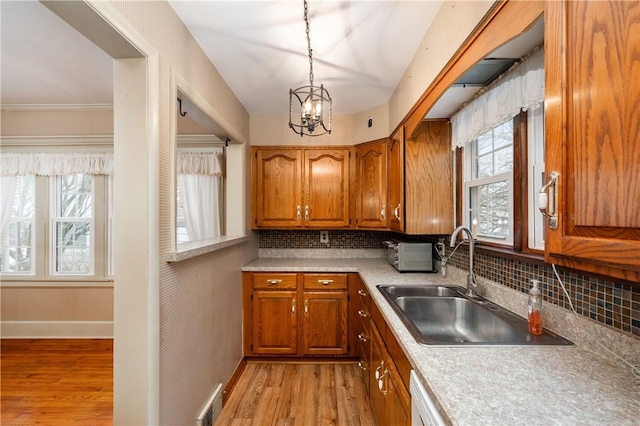 kitchen featuring a healthy amount of sunlight, sink, light hardwood / wood-style floors, and decorative light fixtures